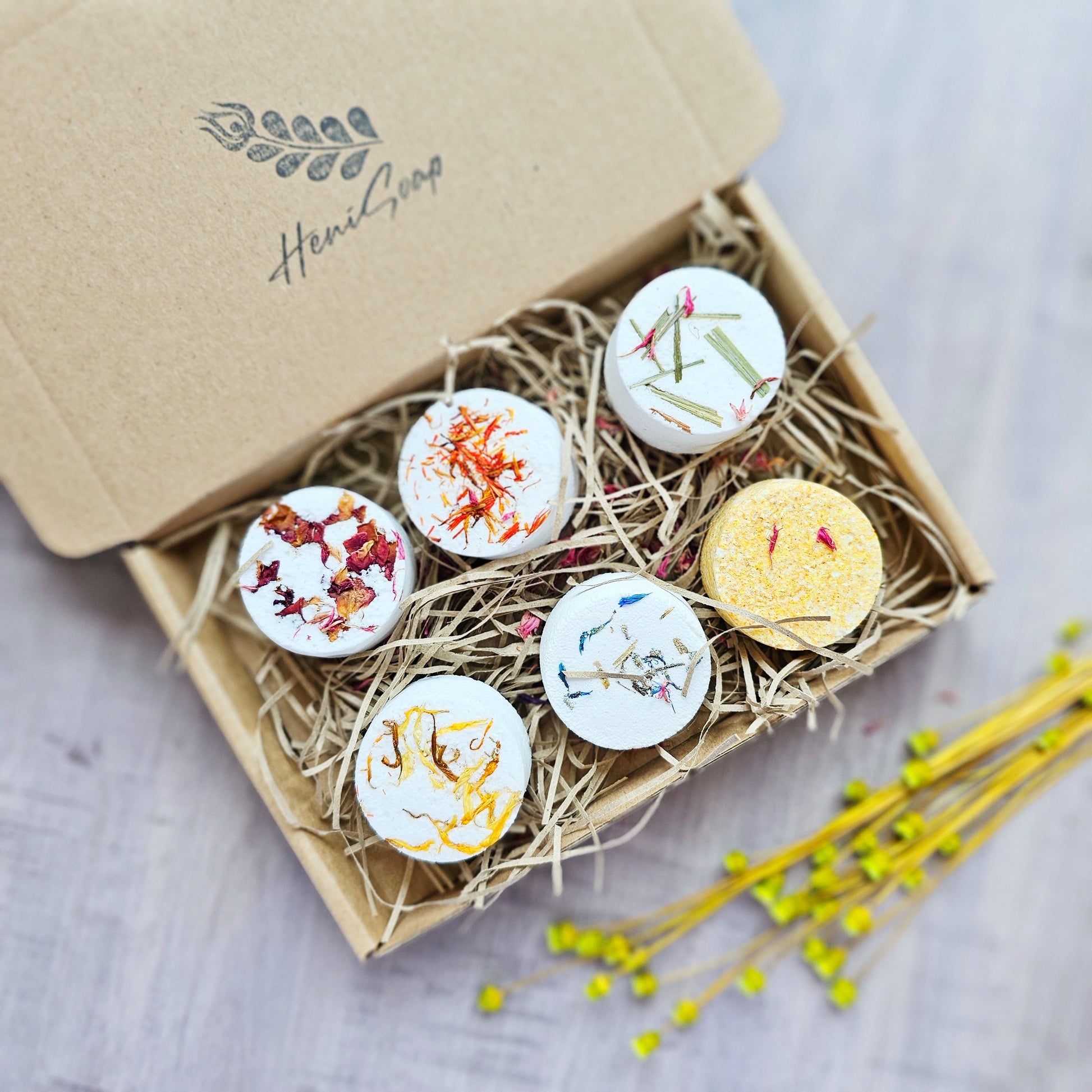 Box of decorative bath bombs with floral designs on a wooden surface