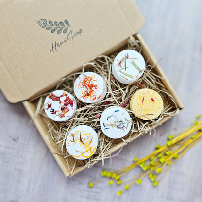 Box of decorative bath bombs with floral designs on a wooden surface