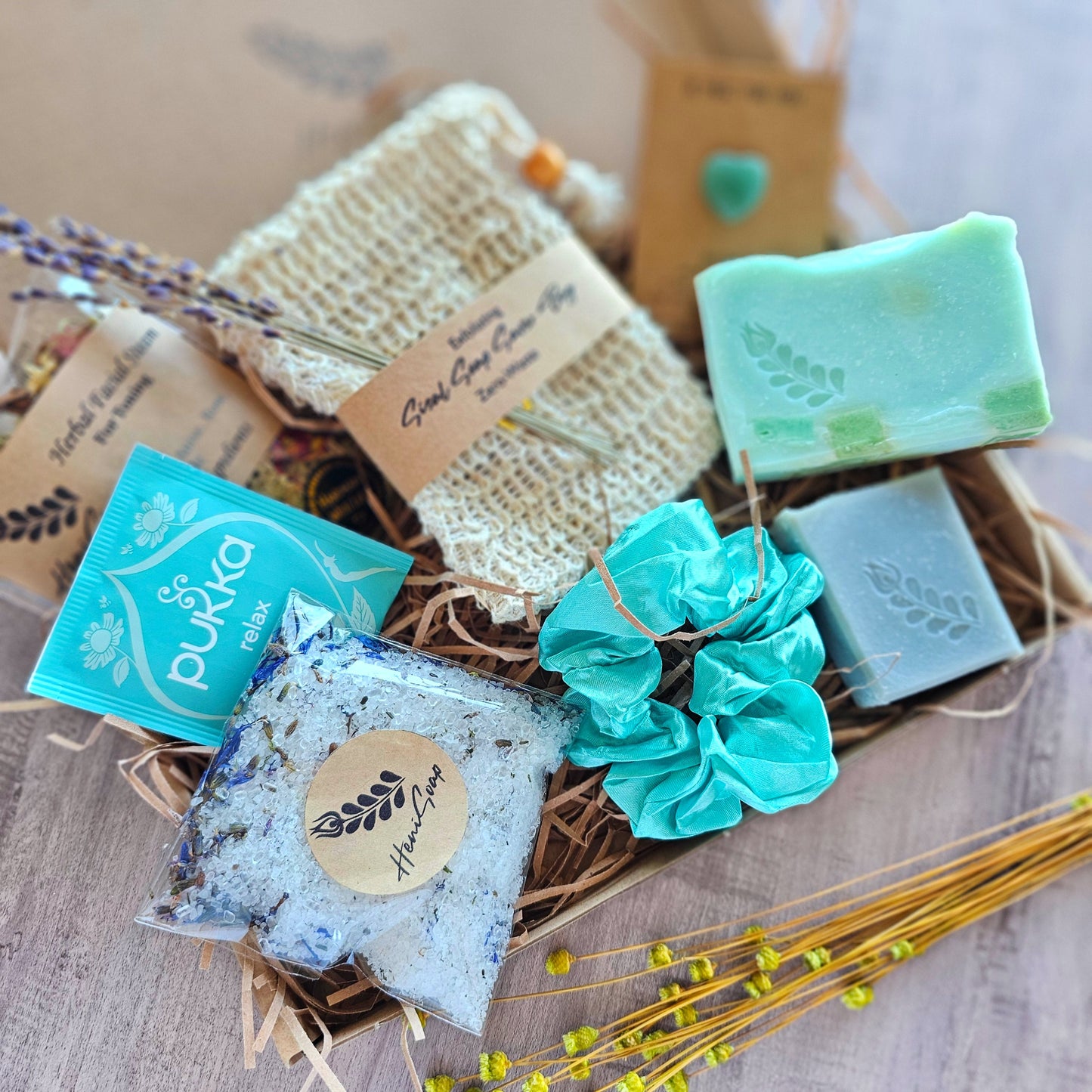 Assorted soaps with visible branding in a decorative box on a textured surface.