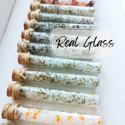 Set of glass vials with cork stoppers containing bath salts on a white background, labeled 'Real Glass'.