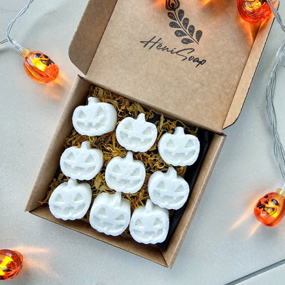 Box of white pumpkin-shaped bath bombs with 'Heni Soap' branding, surrounded by Halloween lights.