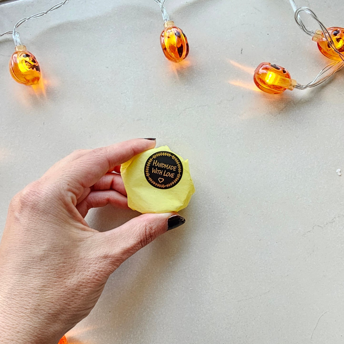 Hand holding a yellow shower steamer with a brand label 