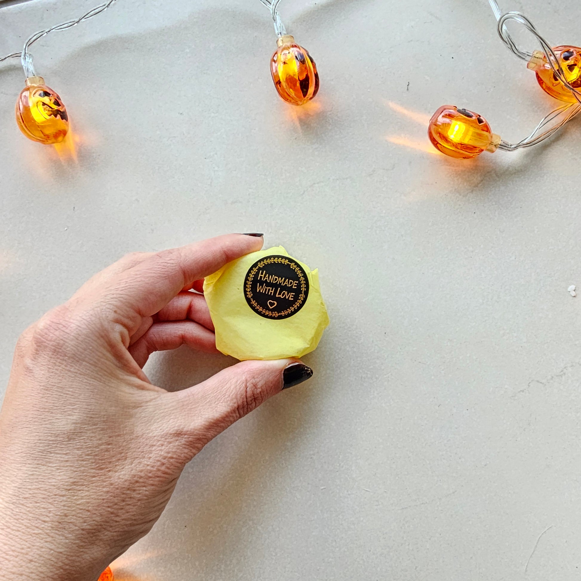 Hand holding a yellow shower steamer with a brand label 