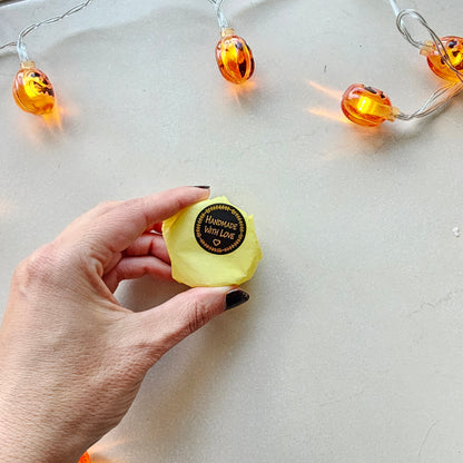 Hand holding a yellow shower steamer with a brand label 