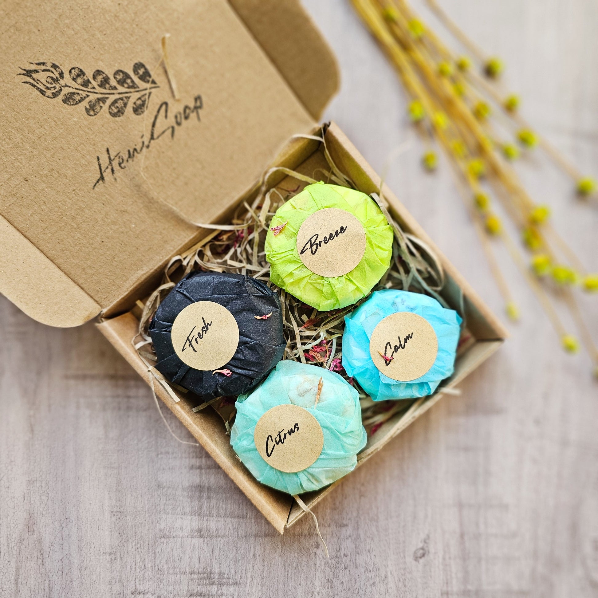 Colorful shower steamers with labels in a cardboard box on a wooden surface