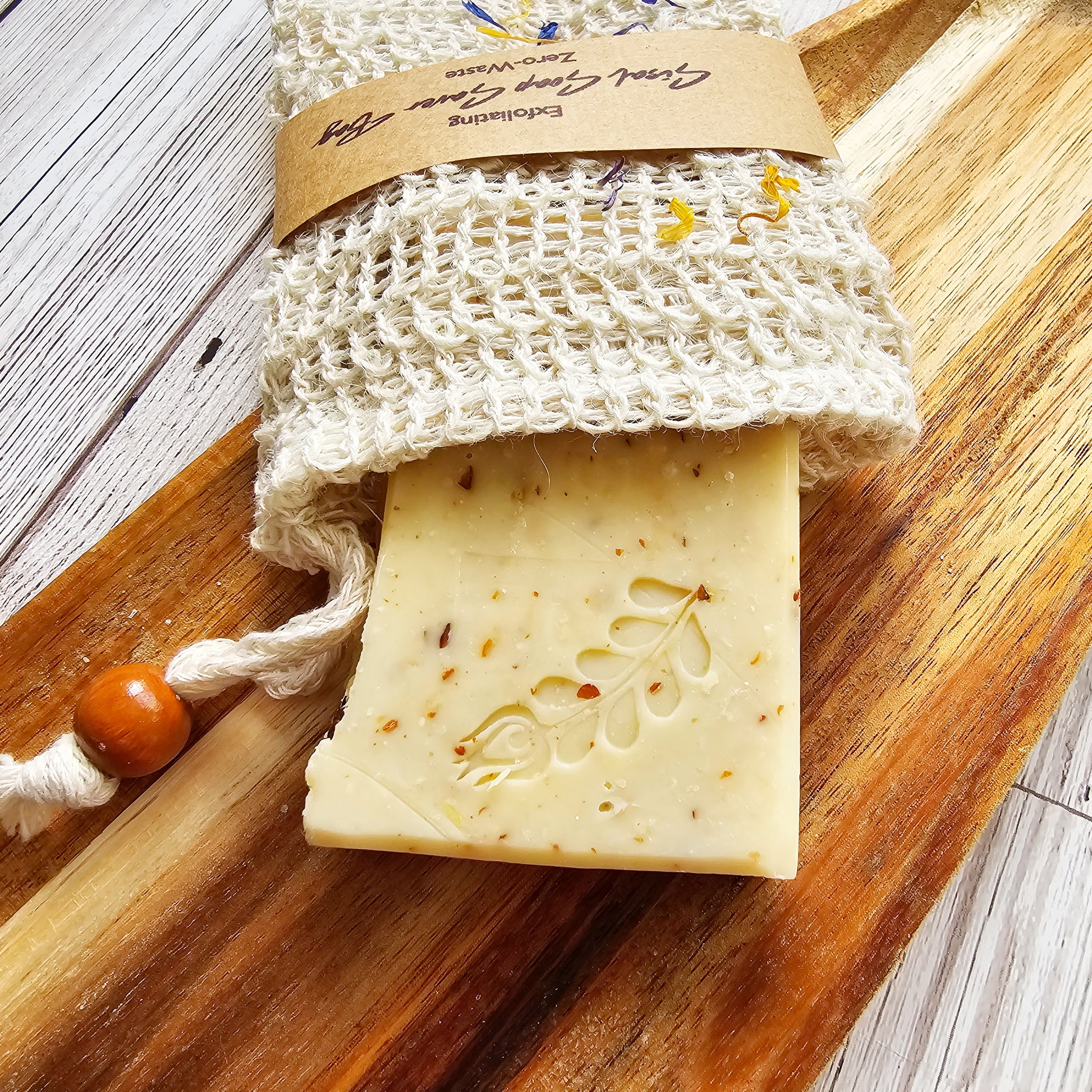 Bar of soap with a textured surface on a wooden board, accompanied by a natural fiber soap bag.